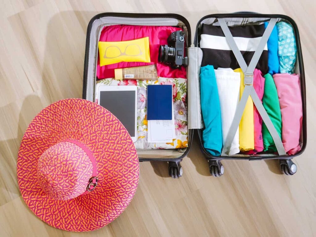 A travel luggage opened wide with ladies sun screen hat near 