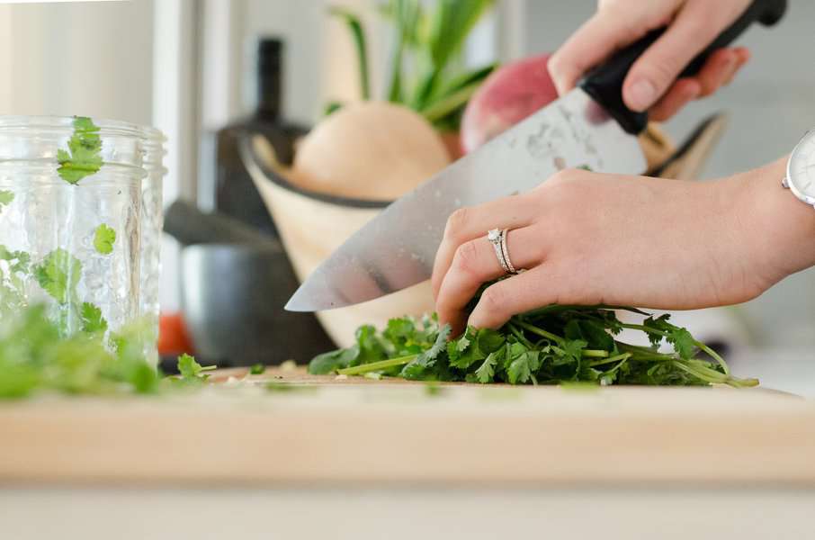 a woman cutting mint leaves in a cooking class