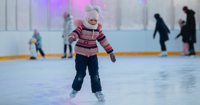 A little girl learn to skate first time at the ice ring