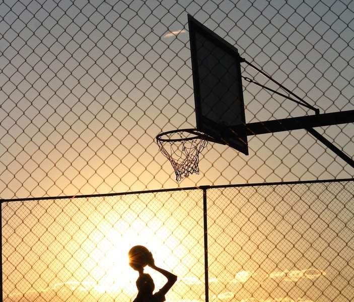 A man playing basket ball at sunrise time