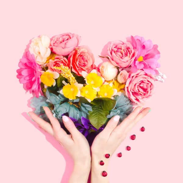 a woman holding beautiful roses in a hand heart shape