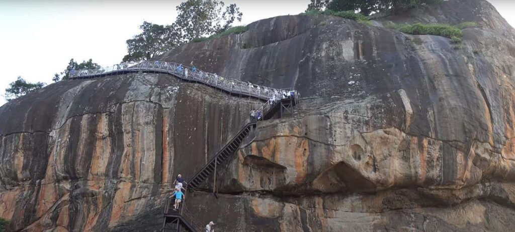 People climbing to the top of the sigiriya rock using steel stairs