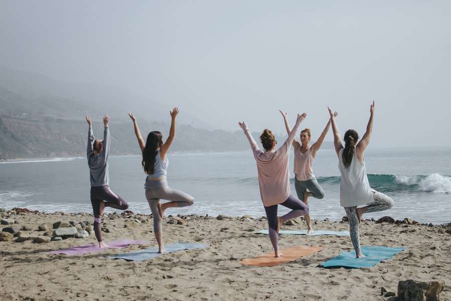 Some people taking yoga classes near the beach