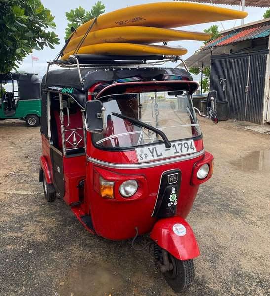 a tuk tuk carrying surfing boards