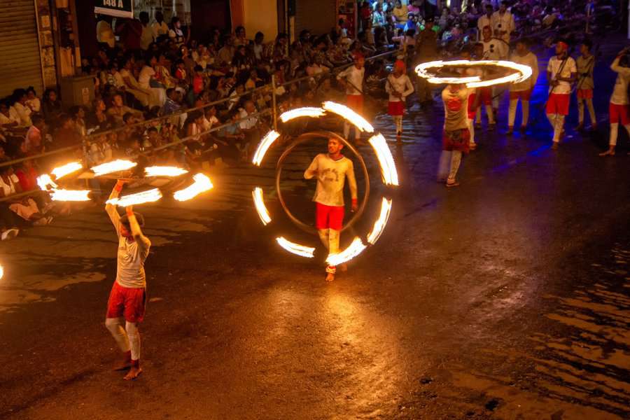 Several dancers dancing with fireworks on the street for the Esala Perahara walk