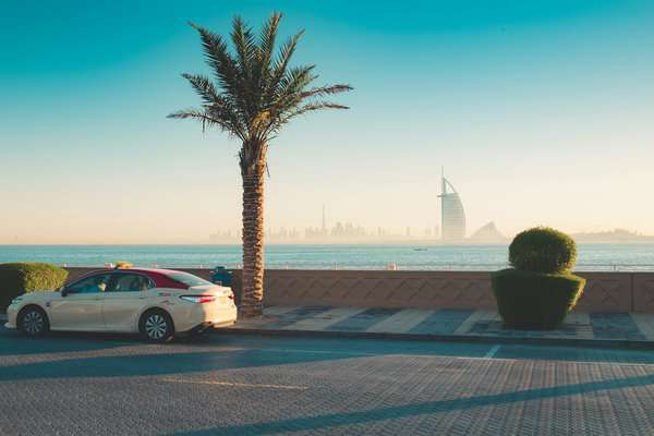 A DTC taxi is parked near the Dubai marina facing the Burj Al Arab