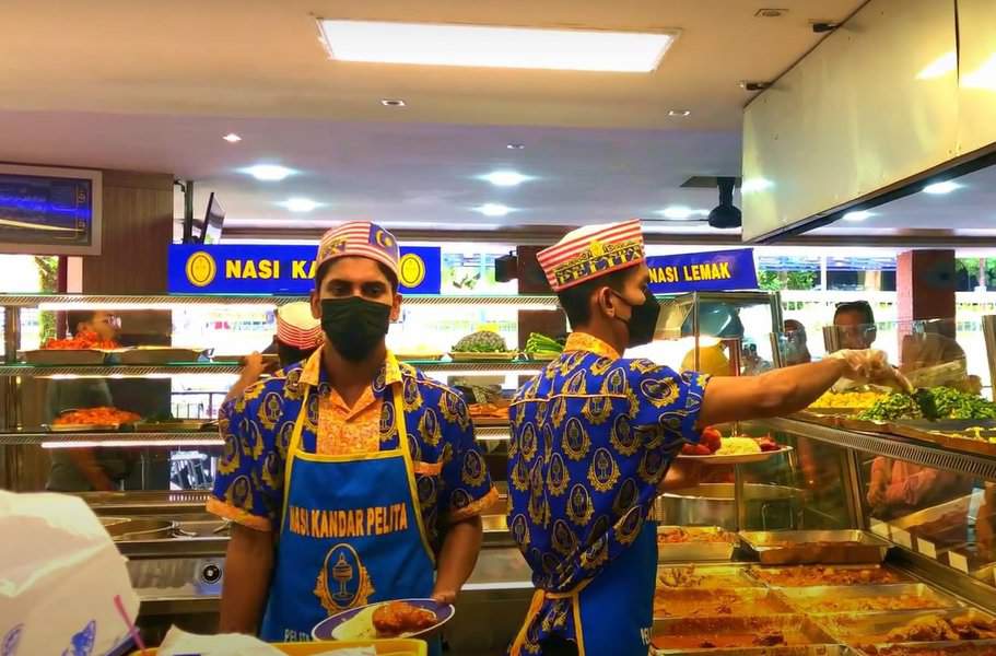 two people serving food in Nasi Kandar Pelita in a traditional uniform